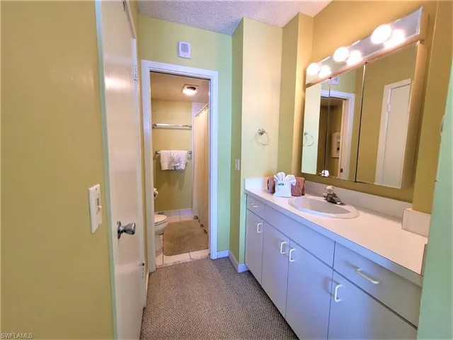 Bathroom with vanity, dark tile patterned floors, a textured ceiling, and curtained shower