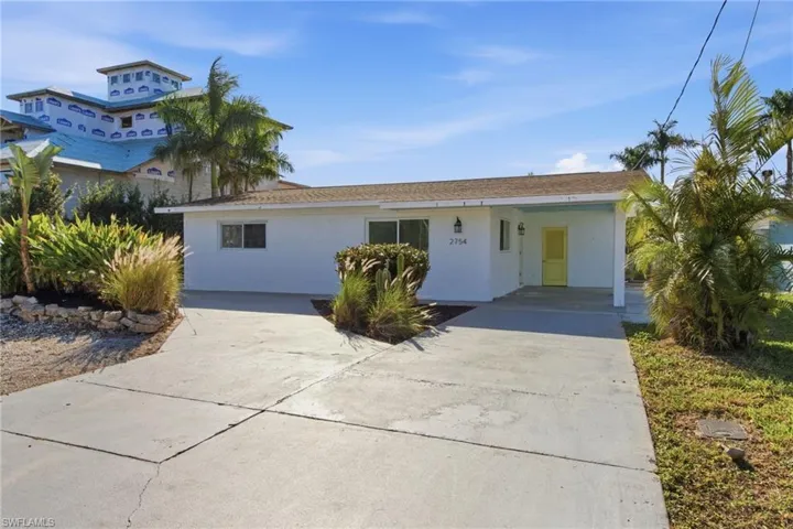 View of front of property with concrete driveway, stucco siding, and a carport