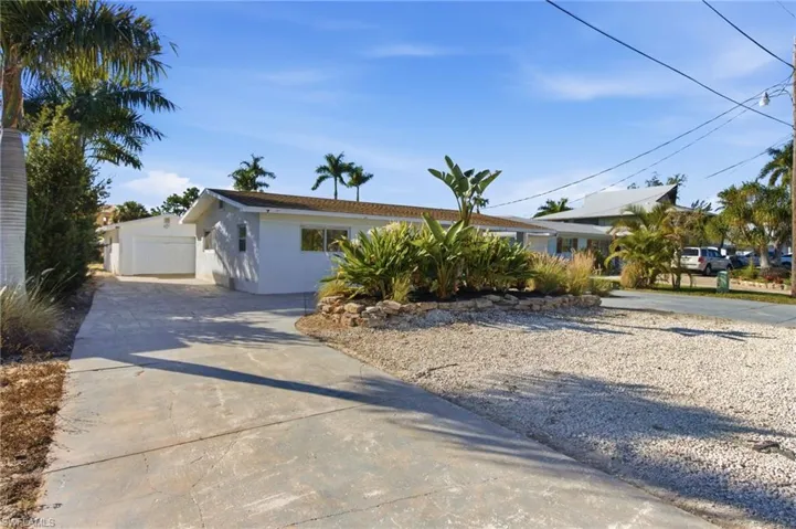 Ranch-style home with stucco siding, a garage, and driveway
