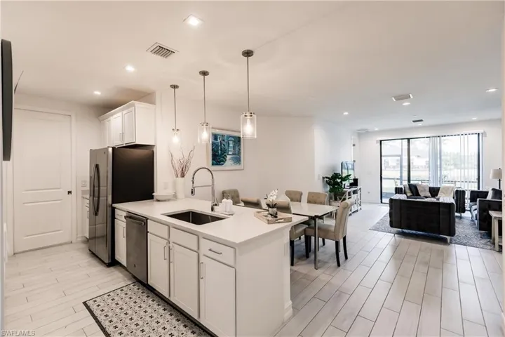 Kitchen with light hardwood / wood-style floors, dishwasher, hanging light fixtures, sink, and white cabinets