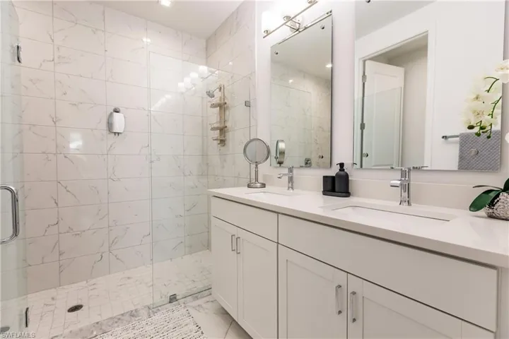 Bathroom with tile floors, a shower with door, and double vanity