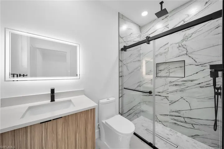 Bathroom with a wood-finish vanity, light-colored countertop, and integrated sink