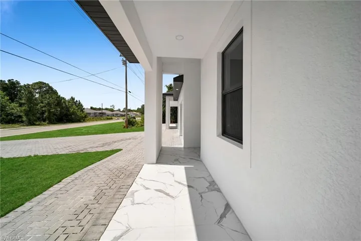 Covered exterior walkway featuring large format white marble-look tile flooring