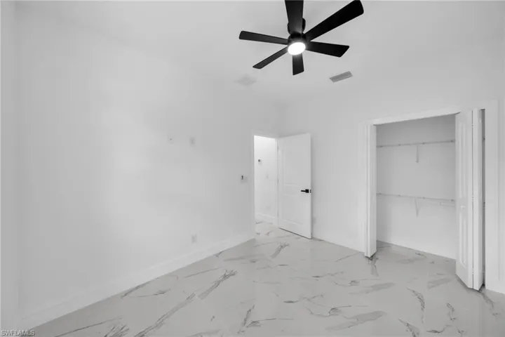 Bright room featuring large format tile flooring, a modern ceiling fan, and a spacious closet with wire shelving