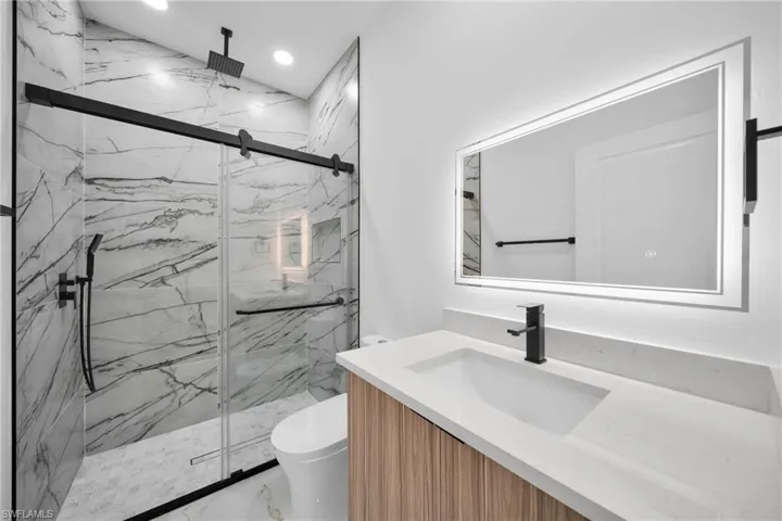 Contemporary bathroom featuring a spacious shower with marble-look tile, a rain showerhead, and a glass sliding door