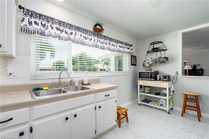 Kitchen featuring white cabinets, light tile patterned flooring, tasteful backsplash, and sink