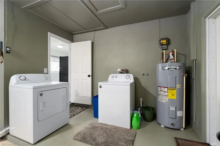 Laundry on raised area in Garage featuring separate washer and dryer and water heater