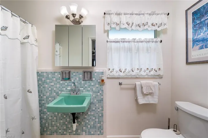 Bathroom with tile walls, tasteful backsplash, toilet, and sink
