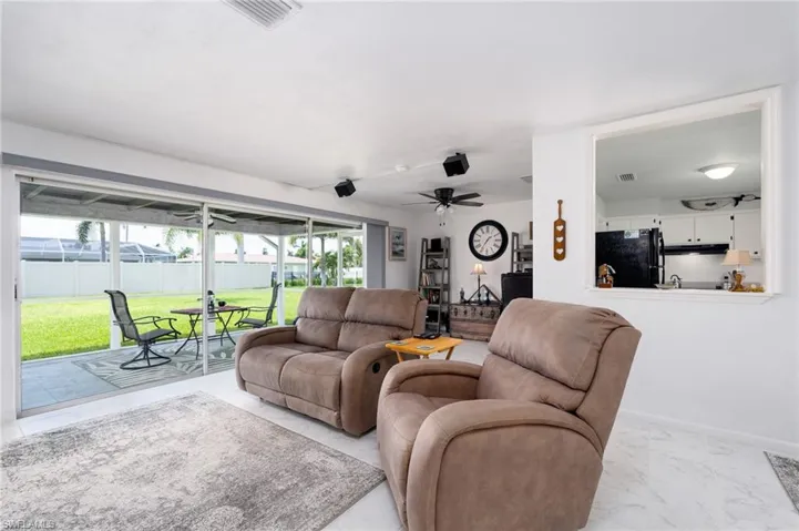 Tiled living room featuring a wealth of natural light and ceiling fan