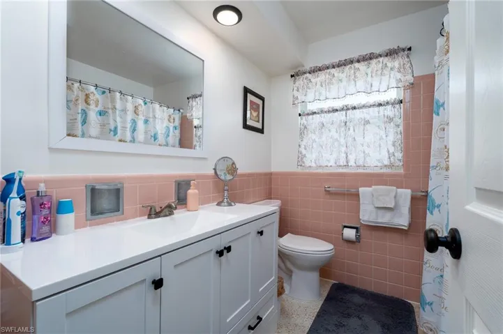 Bathroom with vanity, decorative backsplash, toilet, and tile walls