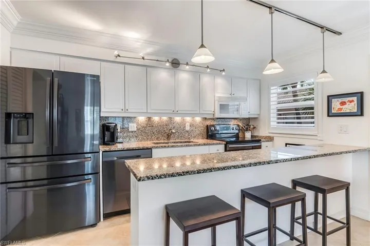 Kitchen with backsplash, rail lighting, electric range, stainless steel dishwasher, and fridge with ice dispenser