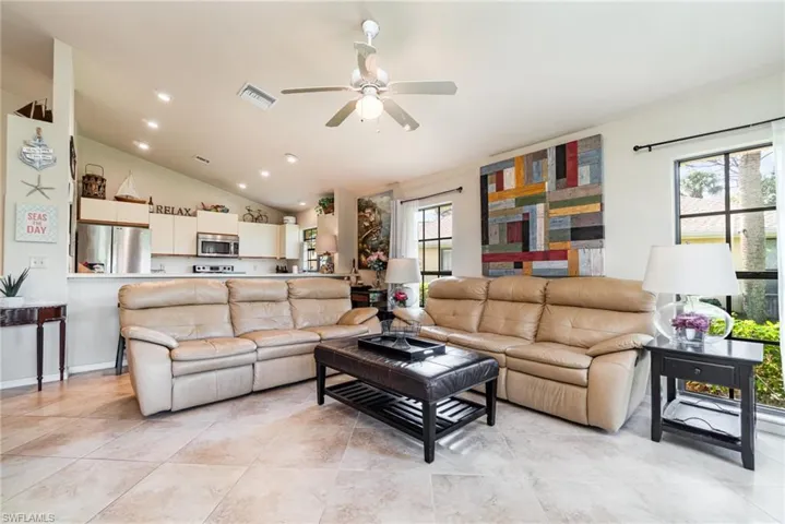 Tiled living room featuring vaulted ceiling, a wealth of natural light, and ceiling fan