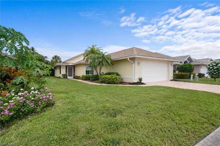 Single story home featuring an attached garage, stucco siding, a front lawn, and driveway