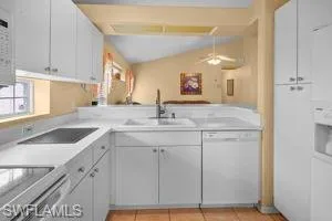 Kitchen with dishwasher, light countertops, white cabinets, ceiling fan, and light tile patterned flooring