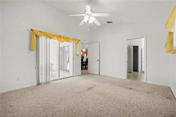 Unfurnished bedroom with light carpet, lofted ceiling, ceiling fan, and access to outside