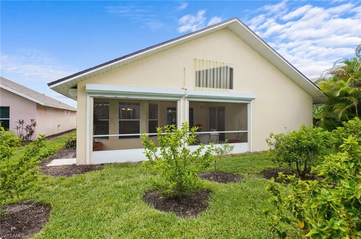 Rear view of house with stucco siding, a sunroom, and a yard