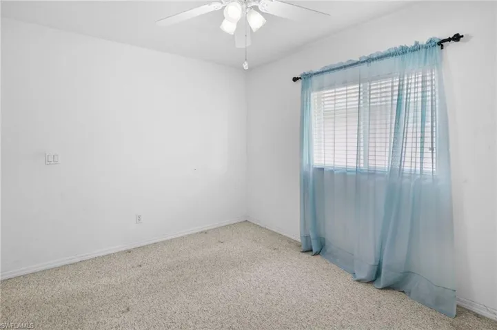 Carpeted spare room with a ceiling fan and baseboards