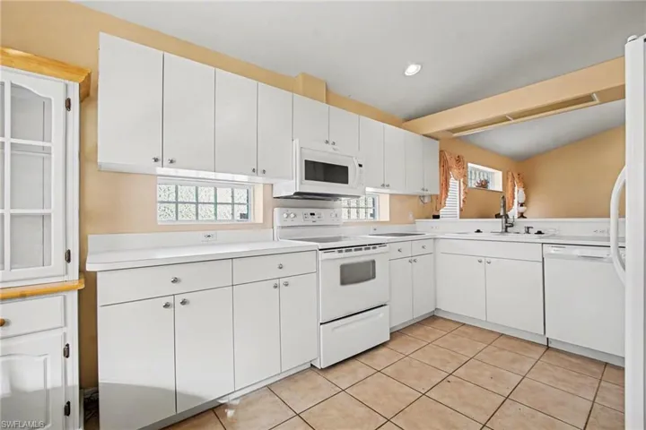 Kitchen featuring white appliances, white cabinets, light countertops, light tile patterned floors, and recessed lighting