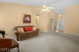 Living area with carpet flooring, vaulted ceiling, and a ceiling fan