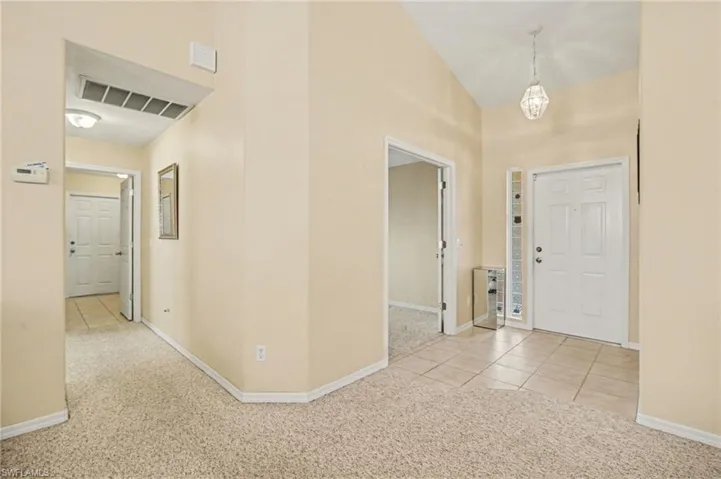 Entryway with light carpet, vaulted ceiling, and light tile patterned floors