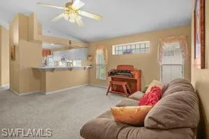 Living area featuring lofted ceiling, carpet flooring, plenty of natural light, and a ceiling fan