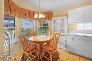Dining area with light tile patterned floors, a chandelier, and lofted ceiling