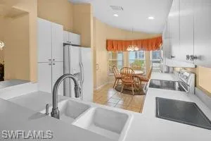 Kitchen with lofted ceiling, light countertops, white cabinetry, range, and white fridge with ice dispenser