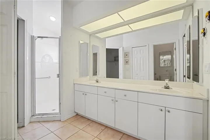 Bathroom featuring a stall shower, double vanity, and light tile patterned floors
