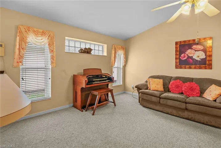 Carpeted living room featuring ceiling fan and lofted ceiling