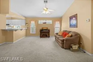 Carpeted living area featuring a ceiling fan and vaulted ceiling