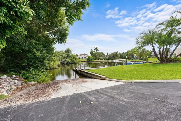 Dock area with a boat ramp, a water view, and a yard