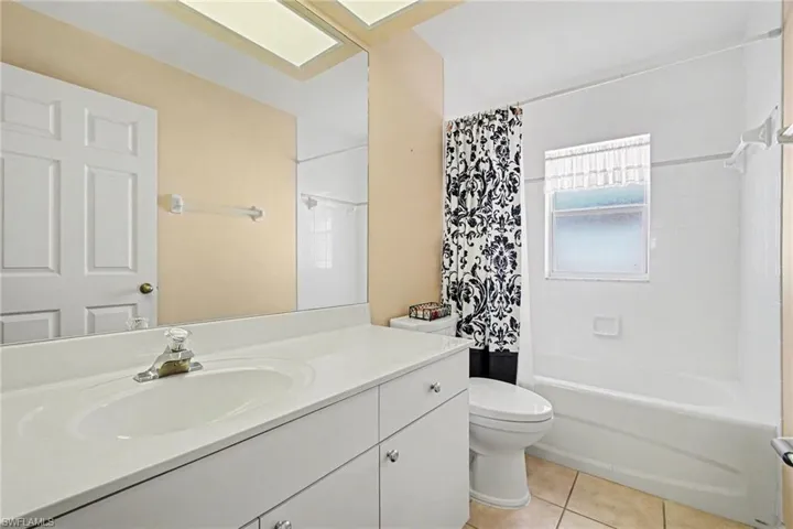 Full bath featuring vanity, shower / tub combo with curtain, and light tile patterned floors