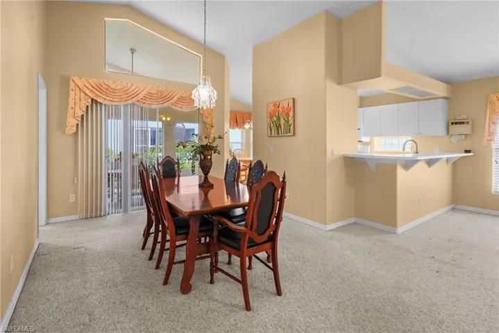 Dining room featuring light carpet, a chandelier, and lofted ceiling