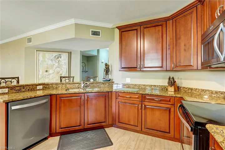 Kitchen featuring wood cabinetry, granite countertops, stainless steel dishwasher, and built-in microwave