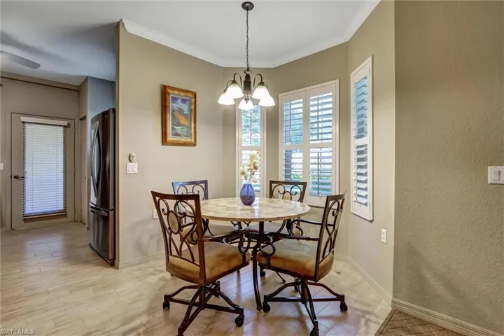Dining area featuring a bay window with plantation shutters, a pendant light fixture, and tile flooring