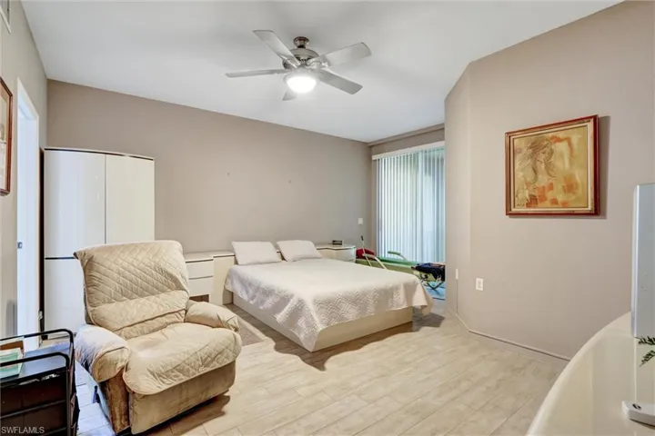 Wood-finish flooring, ceiling fan with integrated lighting, built-in storage cabinetry, and sliding glass door