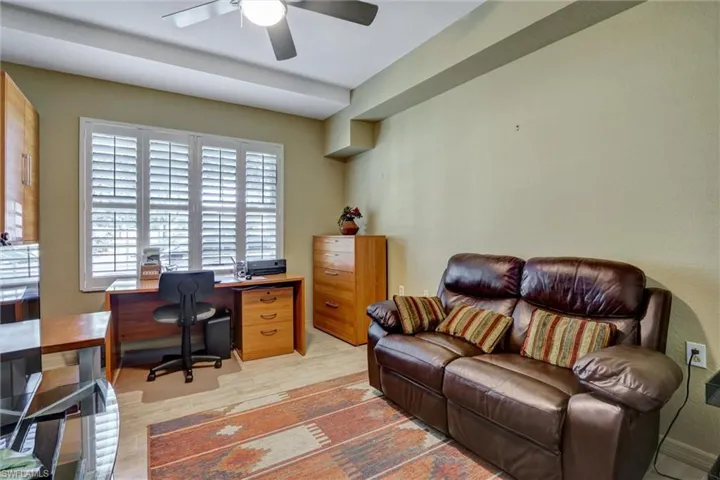 Window with white plantation shutters, ceiling fan with integrated lighting, and light-toned flooring