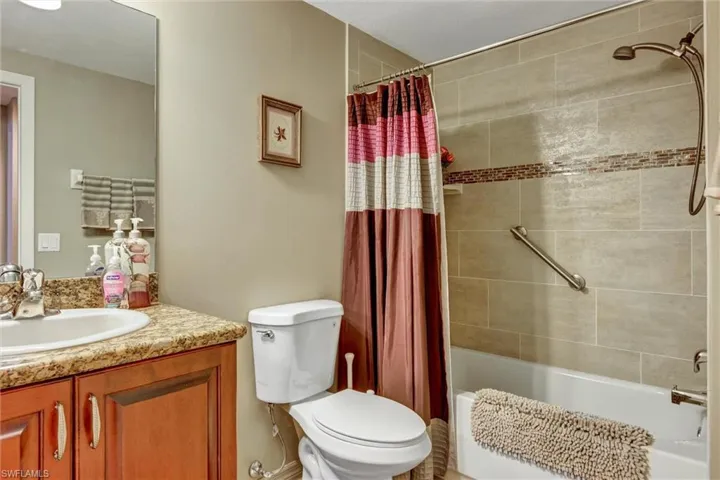 Bathroom featuring a shower-tub combination with a tiled surround, integrated shower head, and a vanity with a counter and under-sink cabinetry