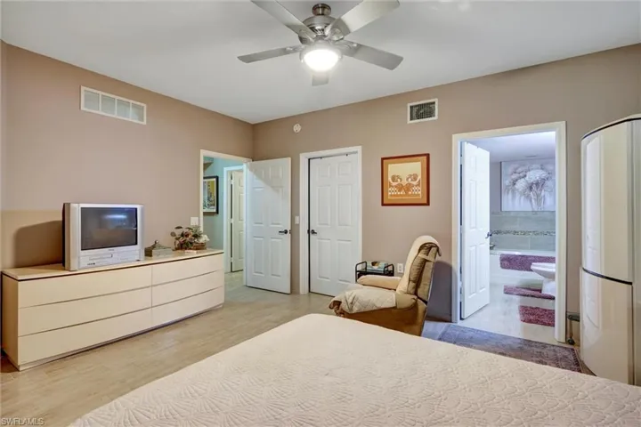 Recessed ceiling, wood-finish flooring, ceiling fan with integrated lighting, multiple paneled interior doors, and a partial bathroom with a built-in tub