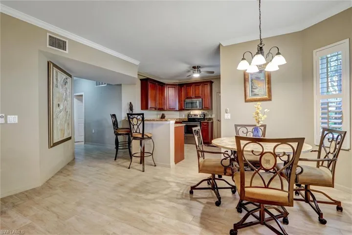 Open-concept kitchen and dining area featuring warm wood cabinetry, stainless steel appliances, and wood-finish flooring