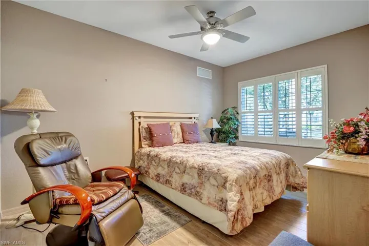 Ceiling fan with integrated lighting, wood-finish flooring, and window with plantation shutters