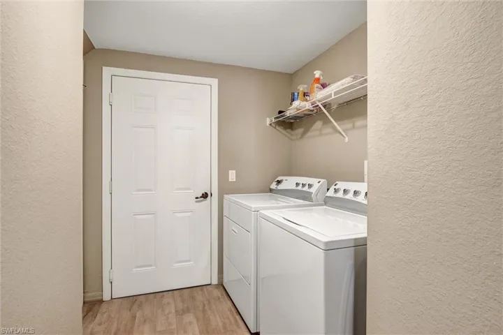 Laundry area featuring wood-finish flooring and a wall-mounted wire shelf