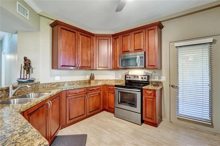 Hardwood cabinetry, granite countertops, stainless steel appliances, ceramic tile flooring, and a ceiling fan