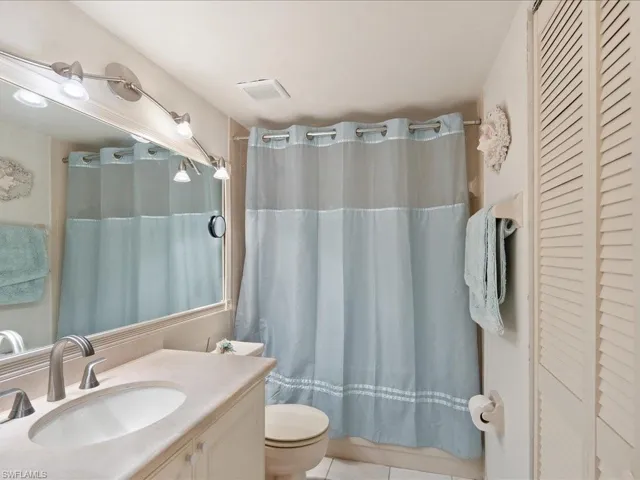Renovated guest bath with new vanity, Corian counter, tub and shower, decor lights and mirror.