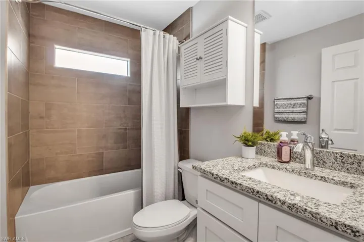 Full bathroom featuring shower / bathtub combination with curtain, vanity, and toilet