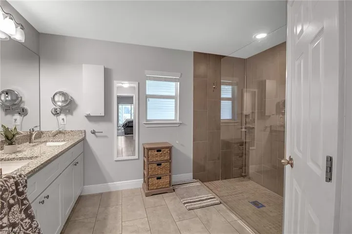 Bathroom with a tile shower, dual vanity, and tile floors