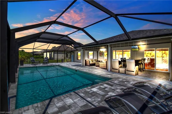 Pool at dusk featuring a patio and glass enclosure