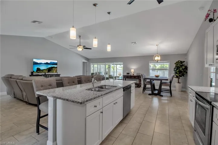 Kitchen featuring white cabinetry, light tile flooring, ceiling fan, and a center island with sink