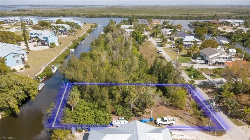 Aerial view of residential area with a nearby body of water and property parcel outlined