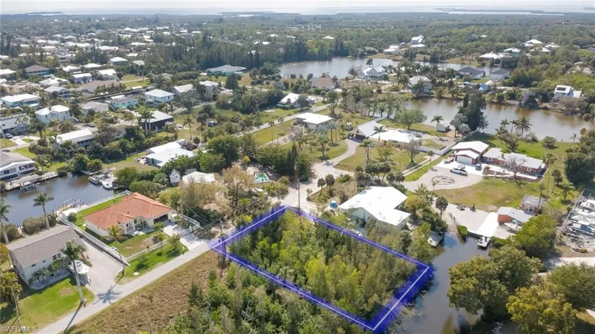 Aerial view of residential area with property boundaries highlighted and a nearby body of water